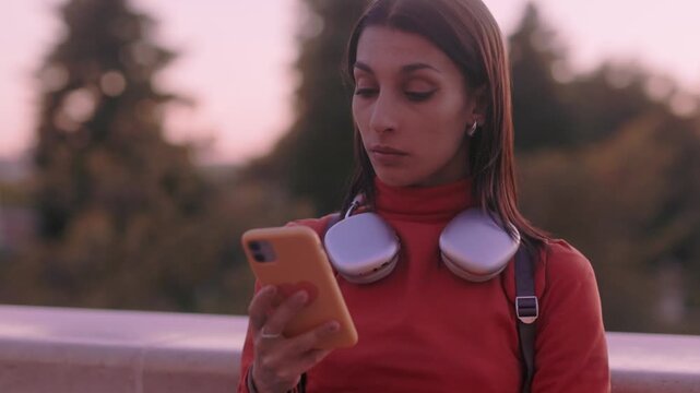 Young university student using smartphone during golden hour sunset