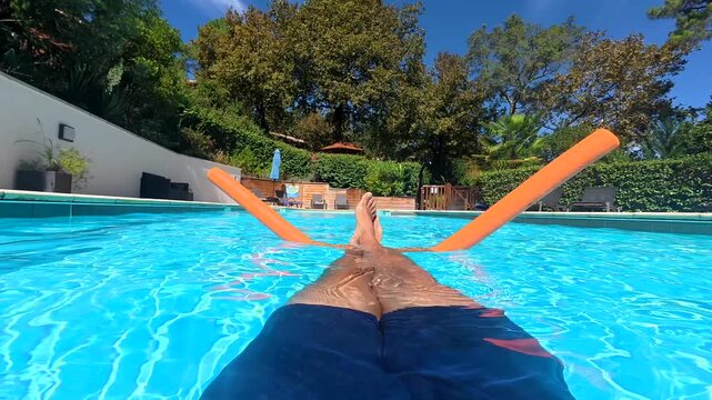 Man relaxing and floating in a swimming pool on a sunny day