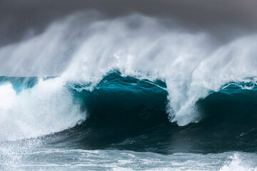 Obraz premium Large ocean wave breaking during heavy swell just after a storm at sunrise, Bronte Beach, Sydney, Australia.