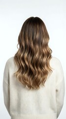 Naklejka premium Woman with long wavy brown hair with blonde highlights wearing cream sweater from behind on white background for hair salon and beauty concepts.