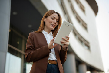 Professional woman using tablet device outside office building