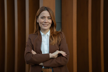 Confident businesswoman smiling, hands crossed, standing outdoors