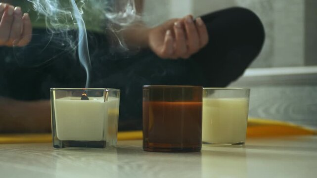 Close up of smoke rising from candle after flame extinguished during meditation or yoga practice at home. Calm peaceful atmosphere, mindfulness, relaxation and wellness concept 