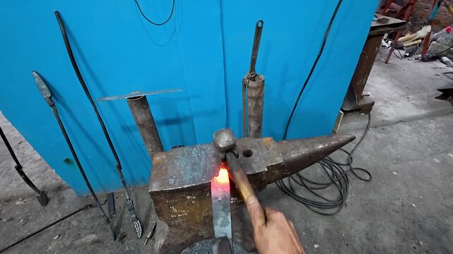 First-person view of metal forging: Traditional bladesmithing techniques in a professional workshop.