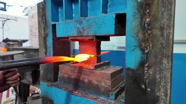 Industrial forging process: High-pressure machinery compressing red-hot metal for knife making.