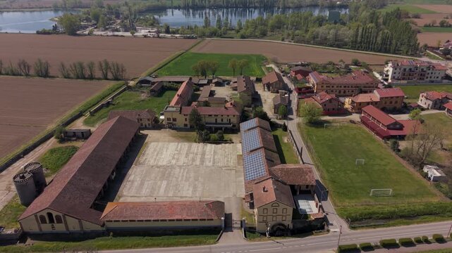 Aerial perspective of a historic agricultural complex in Robbiano di Mediglia, Italy. Multiple farm buildings, courtyards, and old mill highlight long-standing farming traditions.