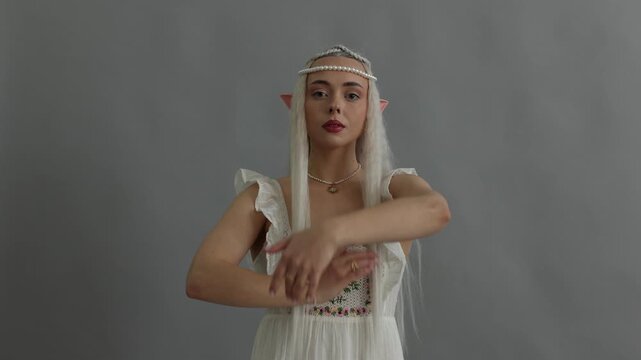 Beautiful girl dressed as elf on grey background