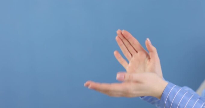 Woman clapping hands on blue background, closeup