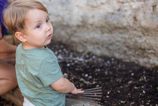 Child using a hand rake to plant