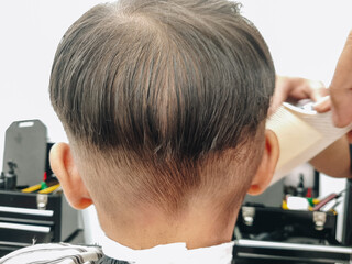 Naklejka premium A boy is having his hair cut at a barbershop.