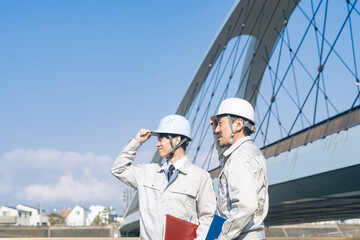 橋の前に立つ男性作業員のグループ