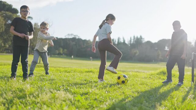 Children playing soccer together in a sunny park