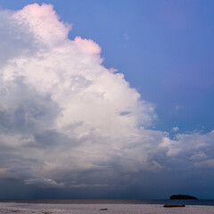 Obraz premium Koh Adang. Tarutao National Marine Park island silhouette. Calm Andaman Sea beneath towering storm cloud. Pink rim lighting on cloud.