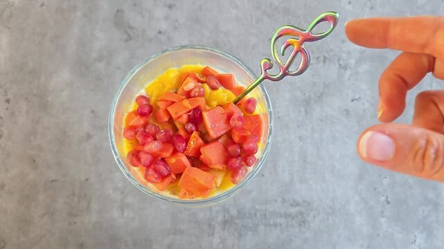 Chia pudding with multi fruit mango, papaya and pomegranate in glass jar. Vegan breakfast concept. Top view on grey marble table