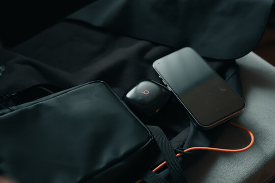 黒いバッグの上に並んだガジェット類とオレンジのケーブル / Everyday carry tech accessories on black bag with orange cable, urban lifestyle concept