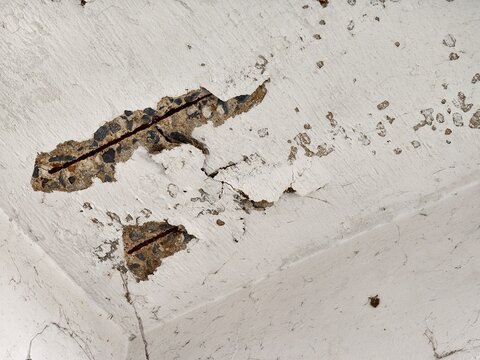 Damaged Concrete Ceiling with Exposed Rusted Rebar and Spalling Texture. building maintenance, construction safety, civil engineering inspections, or urban decay.