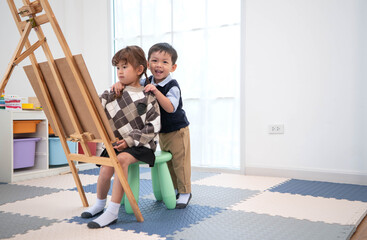Naklejka premium Little boy hugging his sister while drawing together
