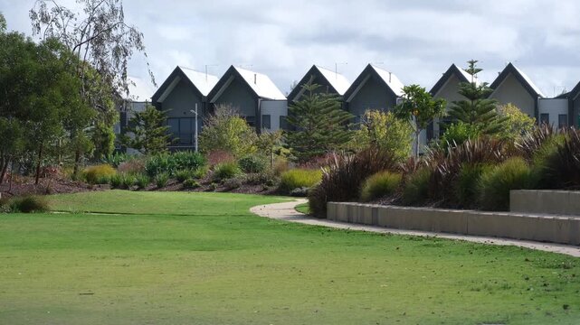 Modern suburban housing or a row of townhouses overlooking landscaped parkland in Werribee, Melbourne, Australia. Residential development, green space integration, livability, contemporary design.
