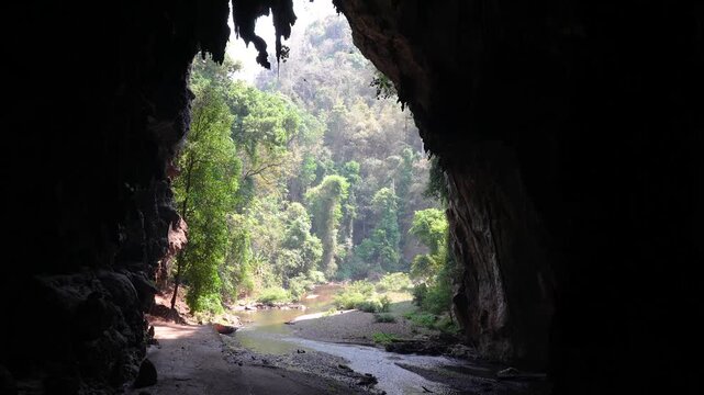 Entrance in exotic cave surrounded by tropical forest, flowing stream and thousands of bats flying inside. Thum Lod Cave in national park of Northern Thailand, popular sightseeing landmark for tourist