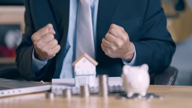 Successful businessman celebrating home loan approval with clenched fists and happy gesture.