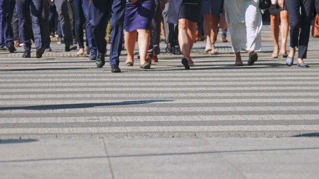 Low-angle, slow-motion shot of diverse professionals in business attire walking across a city crosswalk