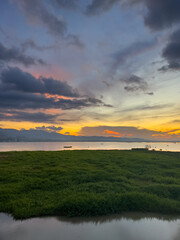 Obraz premium Sunset Over Water With Green Grass