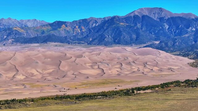 Panoramic aerial view of Great Sand Dunes National Park in Colorado's fall landscapes with stunning aerial views of mountains and fall foliage during morning sunrise light in autumn season - 4K Drone