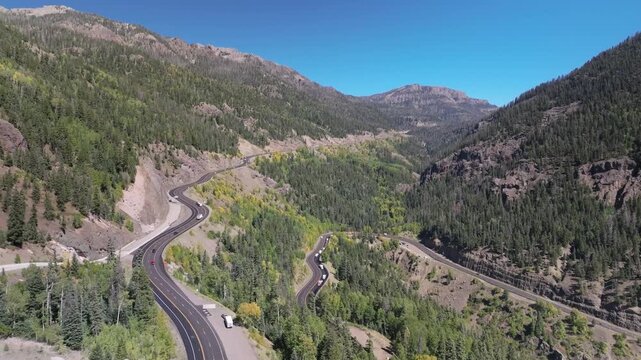 Aerial view of traffic on Highway 160 and Wolf Creek Pass in Pagosa Springs, Colorado fall landscapes capturing winding roads and colorful trees during autumn season - 4K Drone