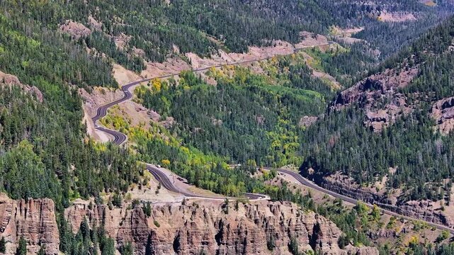 Panoramic aerial view of traffic on Highway 160 and Wolf Creek Pass in Pagosa Springs, Colorado fall landscapes capturing winding roads and colorful trees during autumn season - 4K Drone