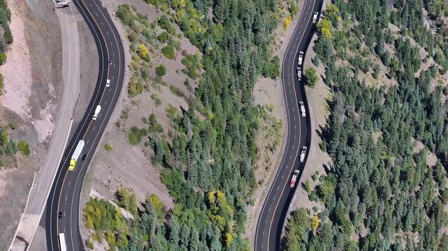 Aerial view of traffic on Highway 160 and Wolf Creek Pass in Pagosa Springs, Colorado fall landscapes capturing winding roads and colorful trees during autumn season - 4K Drone