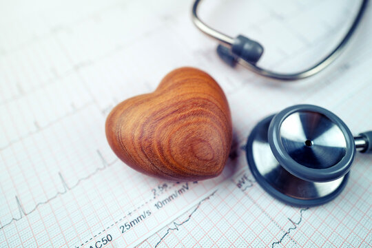 wooden heart and stethoscope on electrocardiogram paper (ECG), heart waves, heart failure, ECG report, medical and healthcare background with life line.