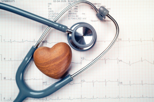 wooden heart and stethoscope on electrocardiogram paper (ECG), heart waves, heart failure, ECG report, medical and healthcare background with life line.
