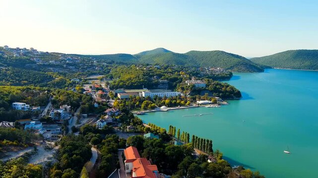 Abrau-Diurso, Krasnodar Krai, Russia. Lake Abrau. Embankment and village. Summer. The text on the embankment translates as the name of the village - Abrau-Diurso. Drone footage