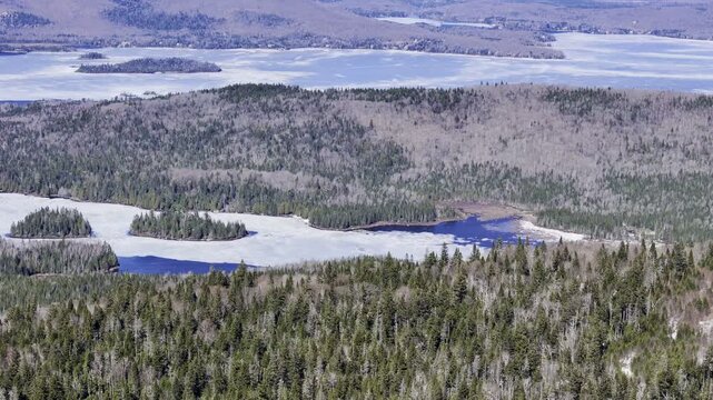 defaultAerial view of winding road along frozen lake in Quebec with forest and mountains under blue sky. g.