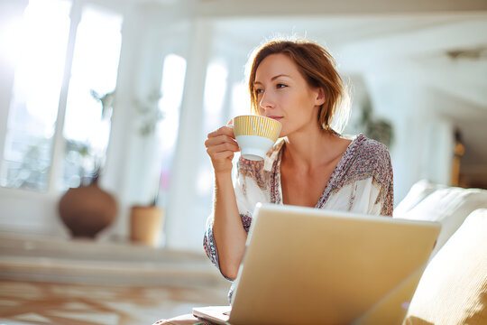 Woman working from home with coffee and laptop, relaxed remote work lifestyle concept