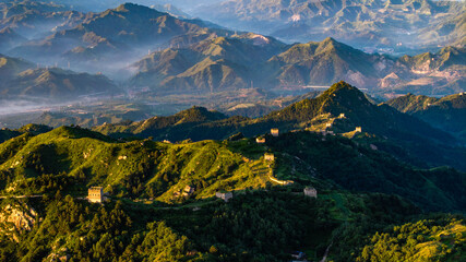 Obraz premium Morning view of the Great Wall in Laiyuan, Hebei Province, China, winding across green mountain ridges under soft light.