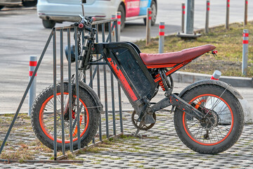 Fototapeta premium An old dirty electric scooter in the bike park on a spring day