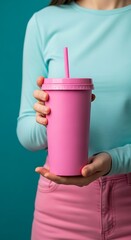 Obraz premium Woman holding a pink tumbler with a straw in light blue and pink outfit