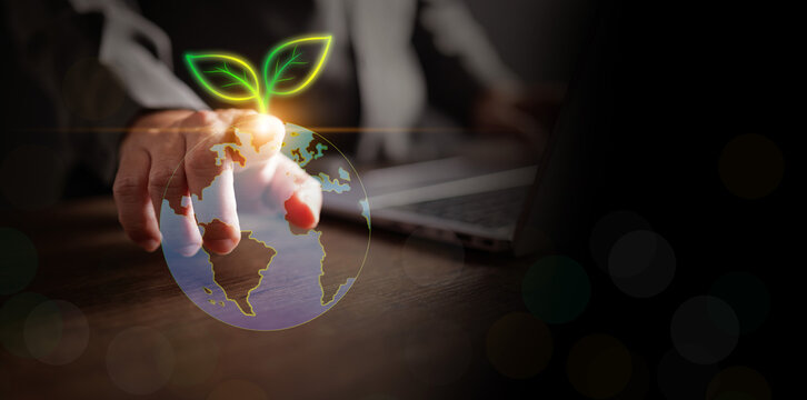 A businessman touching a digital glowing Earth globe with a growing green leaf sprout. Conceptual imagery for global environmental sustainability, corporate social responsibility, and green business.