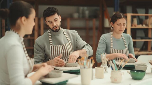 Three pottery workshop workers sculpt from raw clay, form final product. High quality 4k footage