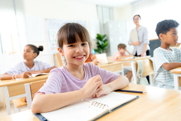 Fototapeta premium Portrait of lovely little girl smile to camera with background of teacher and friends in the classroom.