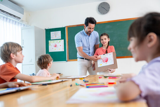 The teacher try to encorage lovely girl to present his painting also explain the meaning of it in front of the classroom and friends also interest in his creation.