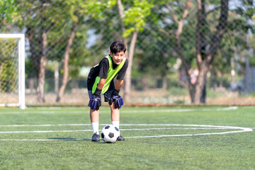 Obraz premium A boy stand and bend the body look like feel tired during practice of soccer ball in the field.