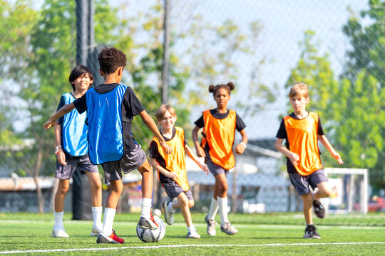 Group of boys and girls enjoy to practice to play soccer together in the field with day light and they look happy to exercise to get good health.
