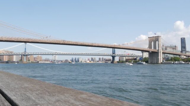 Brooklyn Bridge from Manhattan Downtown, New York City, United States. Bridge to Dumbo from esplanade pier park in NYC USA. American architecture, famous tourist landmark. Waterfront urban promenade.