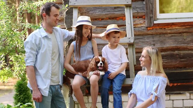 Parents and children sit on stairs outside rustic log house, chatting and spending time together. Concept of family unity and relationships. International Day of Families
