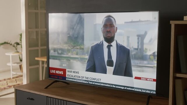 No people shot of smart flat screen TV at family home, displaying news show broadcast, African American male anchor reporting on military conflict, soldiers in camouflage in battle reconnaissance