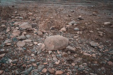 Rocky riverbank with dry grass and muted tones on a cold day © Jezabel