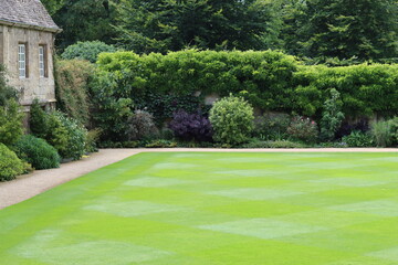 Obraz premium Neatly mown lawn surrounded by a garden path and flower beds