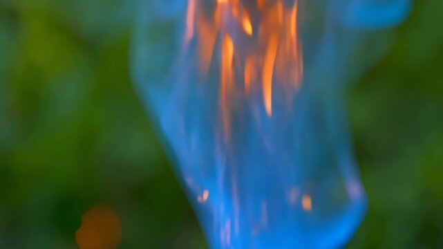A blurred close-up of a blue flame with glowing bokeh lights in the background. 4k Video footage.
